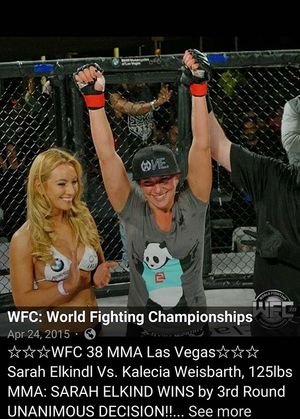 Sarah Elkind has her hand raised in victory